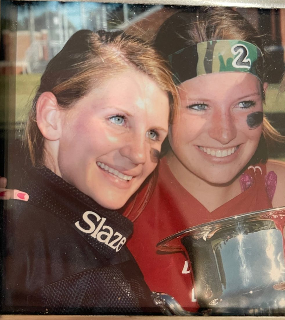 The two of them on a field, eye black on, holding a trophy